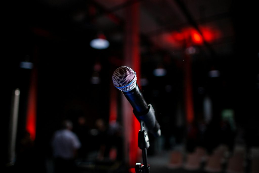 Dynamic photo of a microphone on stage with red backlighting, ideal for live performance themes.